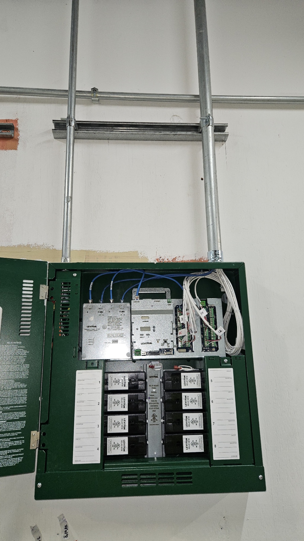 Leviton GreenMAX Relay Panel — Open lighting control relay cabinet with relay modules, network controller, and labeled circuits 1–8.