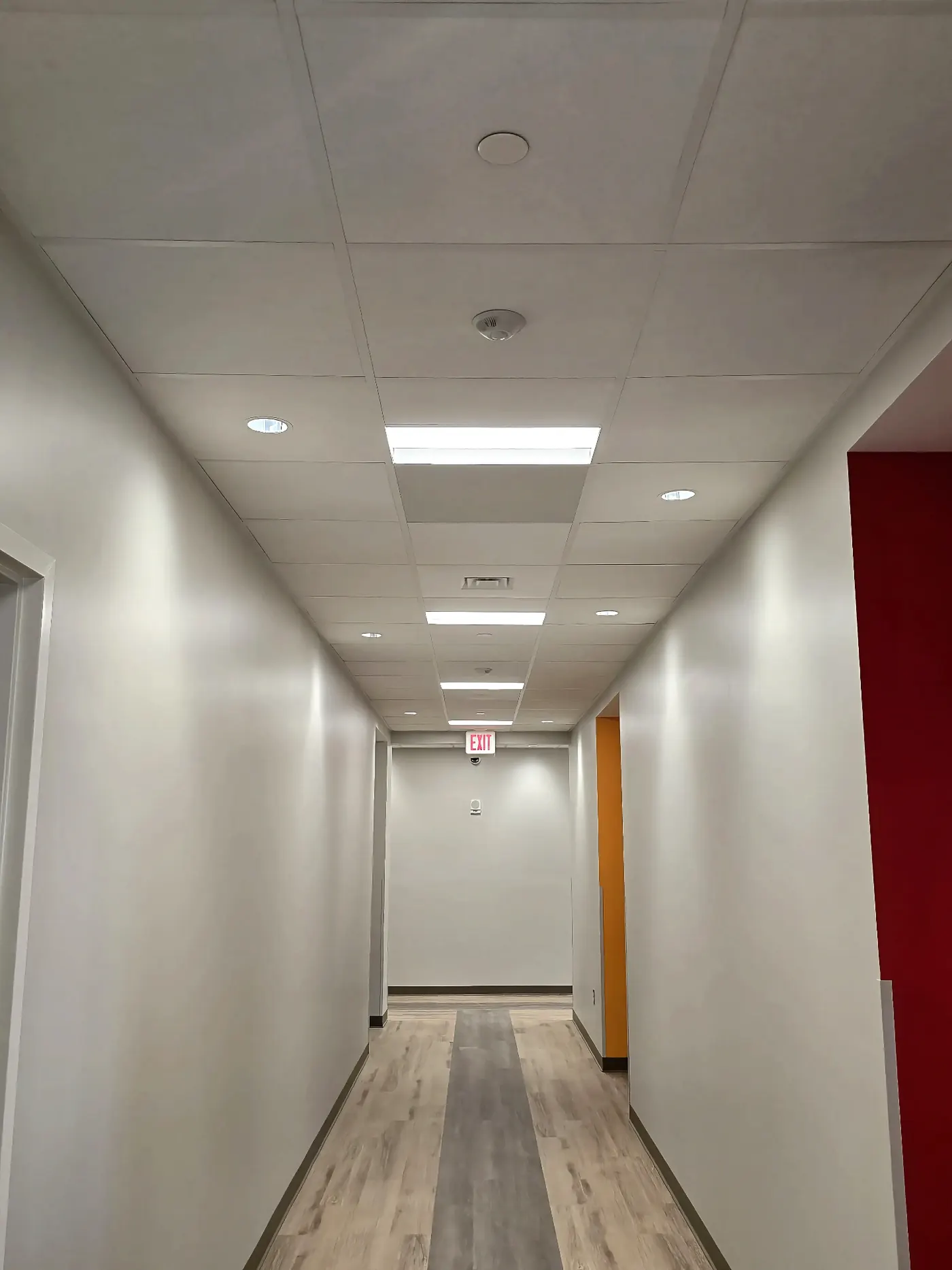 Corridor Lighting & Exit Signage — Mixed recessed cans and LED troffers complete a corridor — code-compliant exit signage included.