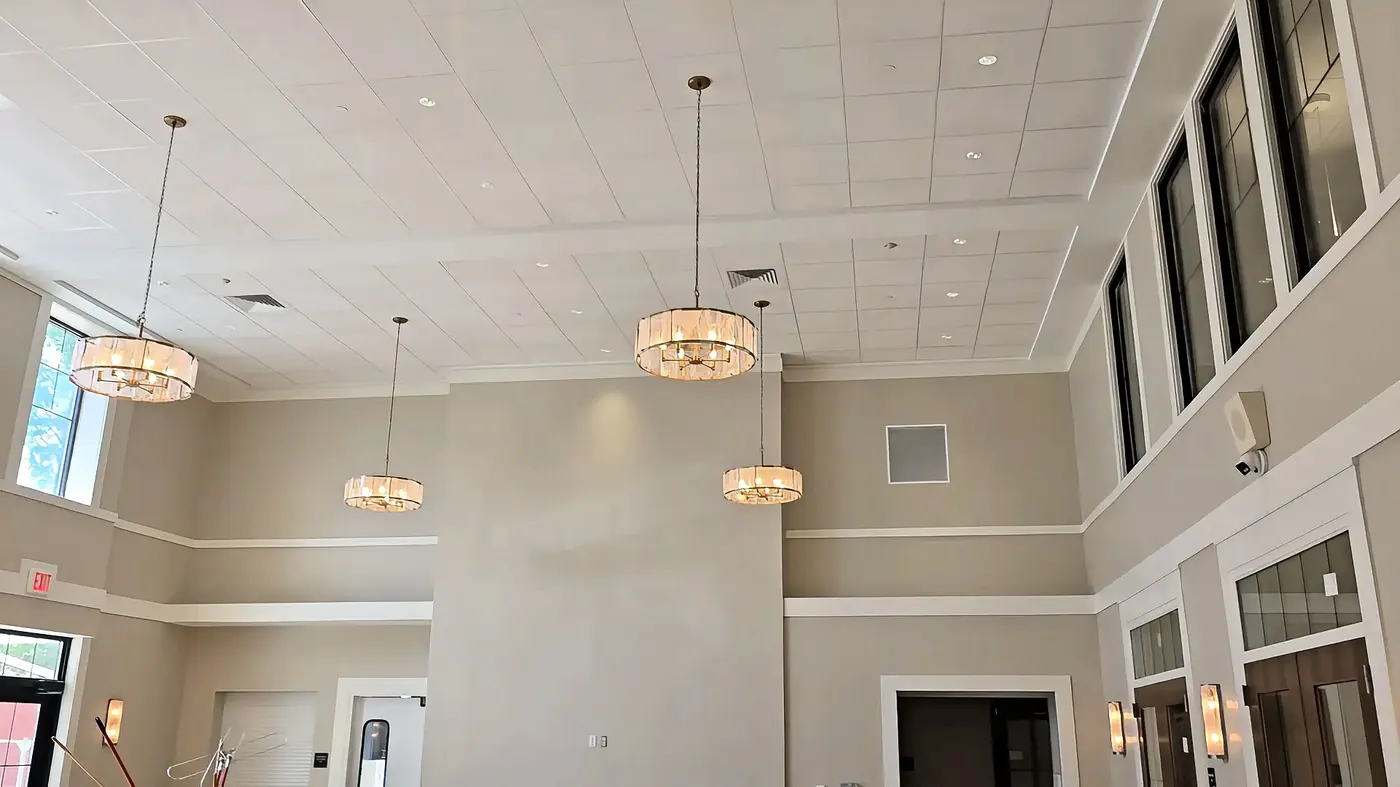 Grand Lobby Chandelier Install — Tall-ceiling lobby finished with multiple drum pendant chandeliers and matched recessed cans.
