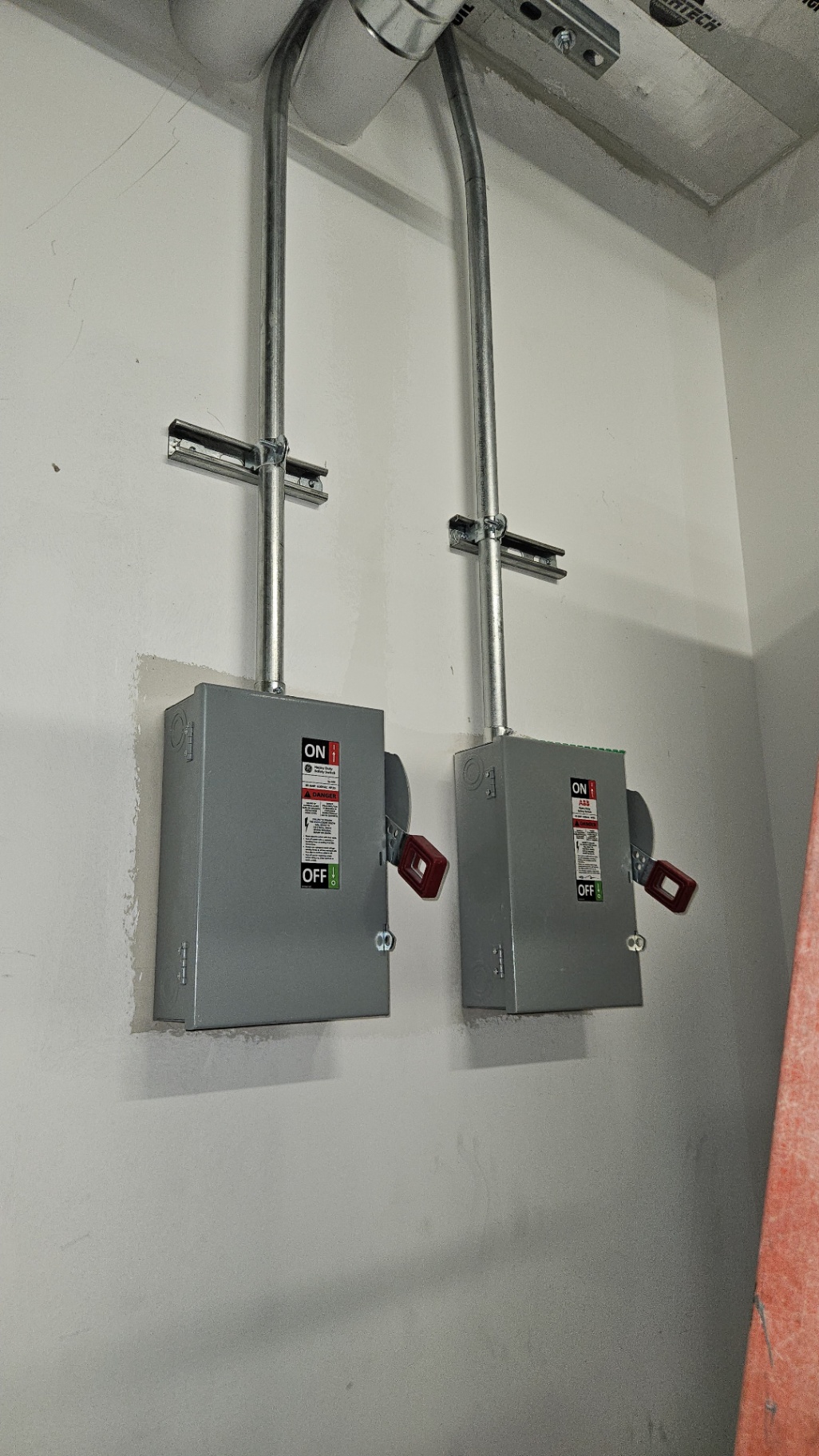 Ceiling-Fed Equipment Safety Disconnects — GE and ABB safety switches strut-mounted with EMT drops from a concrete deck — clean, code-compliant feeds.