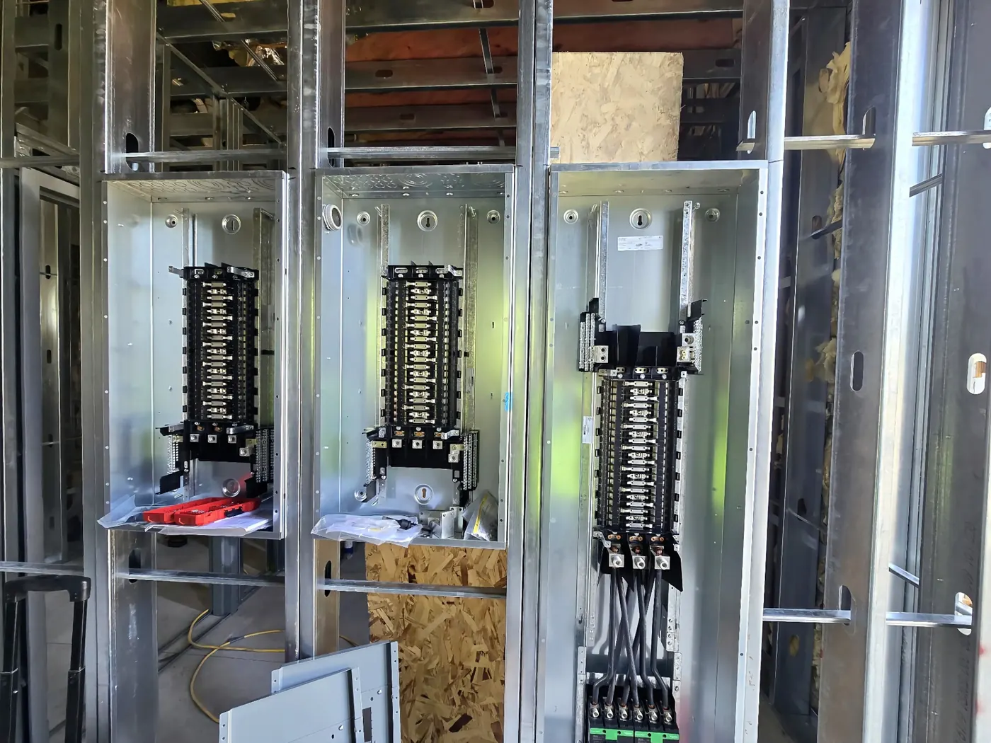 Triple Panelboard Rough-In — Three Schneider panelboards staged side-by-side with EMT homeruns squared and stacked.